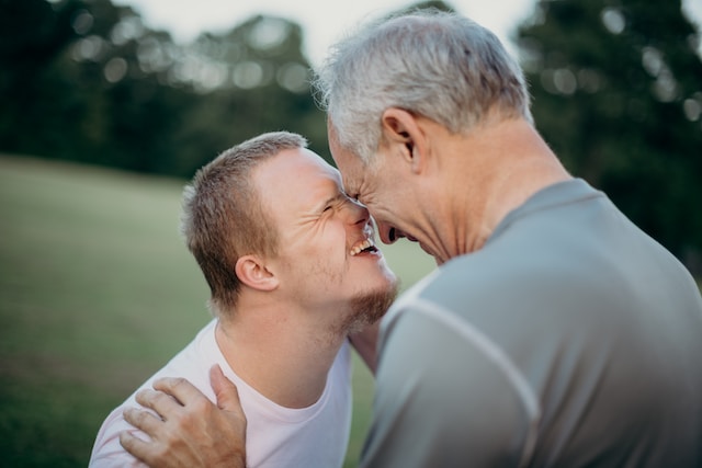 Autistic boy smiling and touching heads with another person