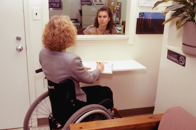 A wheelchair seated woman at a reception desk